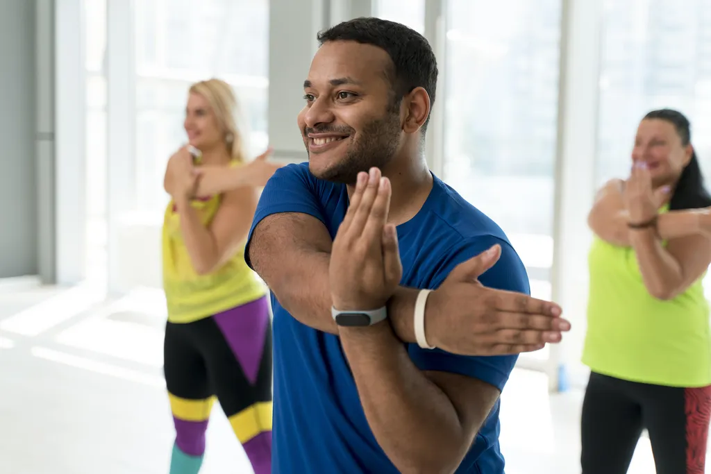 A diverse group of adults warming up together in a gym, ready to exercise.